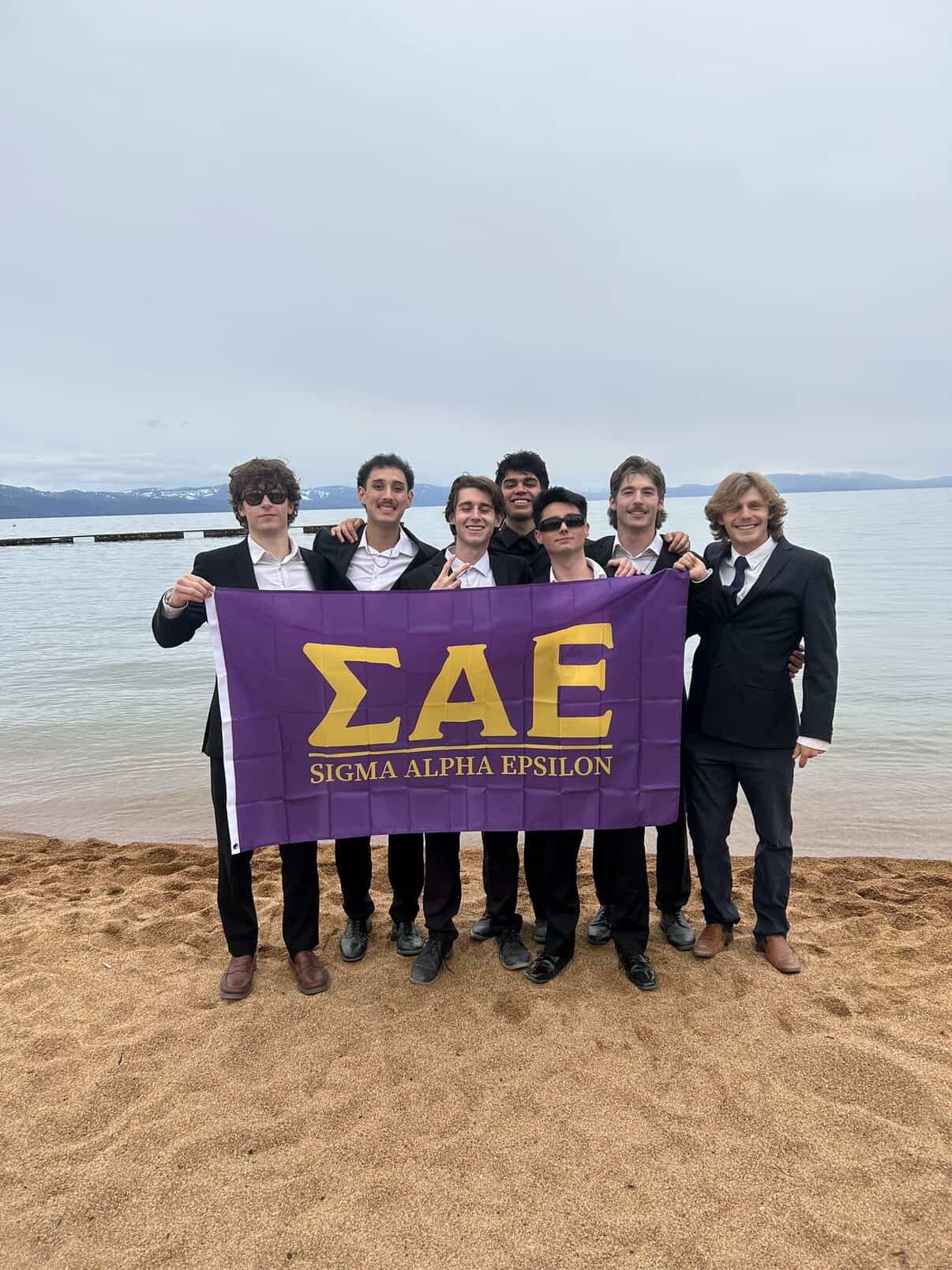 PHI ALPHA MAN group on the beach holding an SAE sign