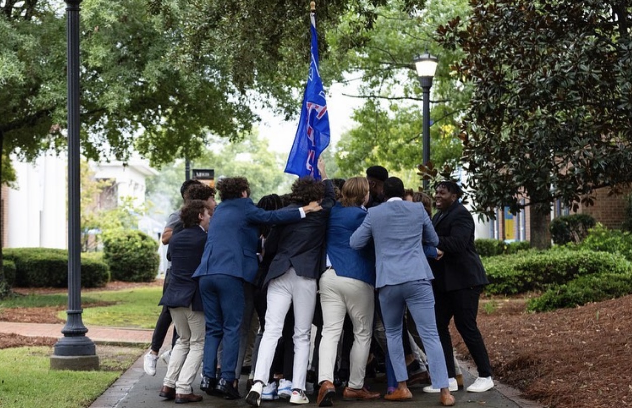 group huddle of SAE brothers around their flag