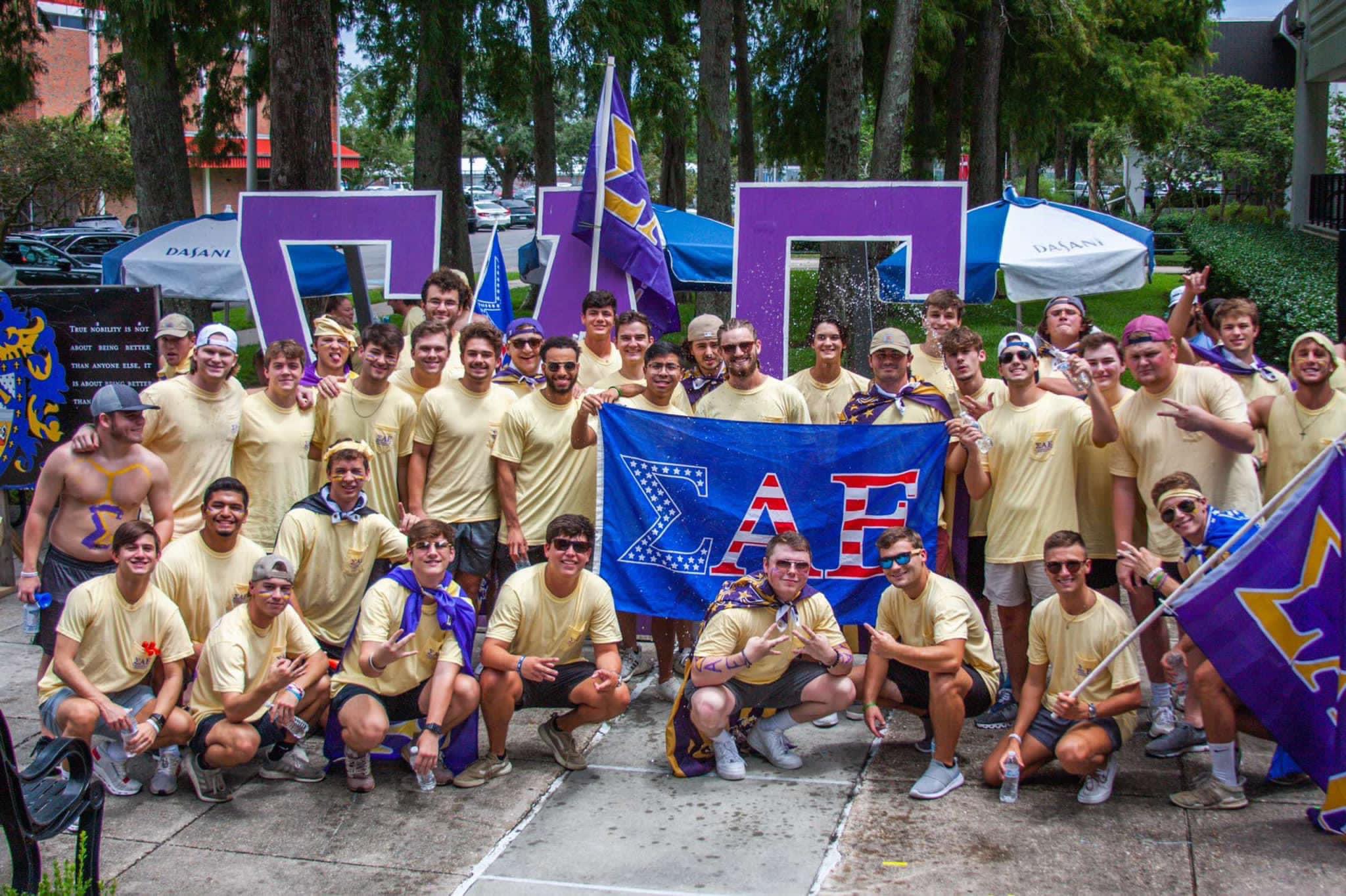 group photo of SAE brothers holding an SAE flag and large greek letters